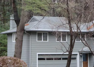 Gutter Cap on a gray house tucked among tall trees