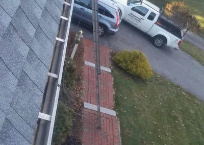 Cleaned gutter line running the length of the roof, truck parked below