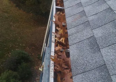 Looking down a long gutter run packed with leaves before cleaning