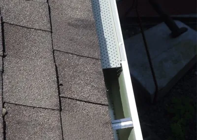 Perforated aluminum gutter screen fastened over a gutter