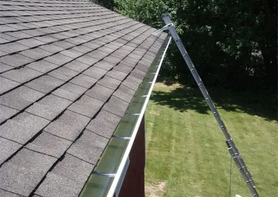 Gutter screens installed along a long roofline, ladder still in place