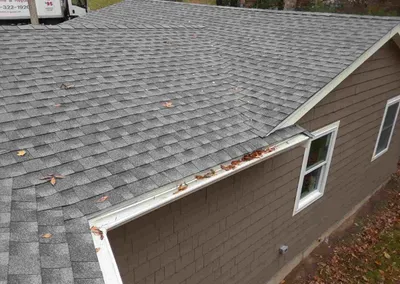 Gutter screens on a brown house with leaves scattered on the roof