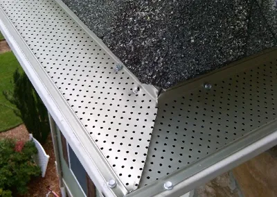 Gutter screen wrapping an outside corner above a stone wall