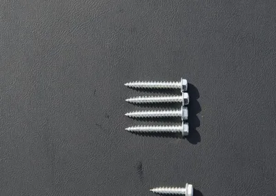Three sizes of gutter screws — 3 inch, 1.25 inch and .75 inch — laid out on a dark background