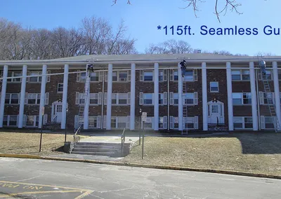 115-foot seamless gutter run across the front of a large brick apartment building