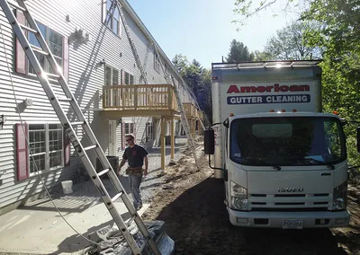 Crew with extension ladders and the American Gutter box truck at a condo building
