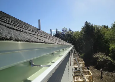 New seamless gutter installed along the roof edge, seen from the roof