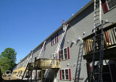 Ladders set against a multi-unit building during a gutter installation