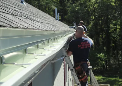 Crew hanging a long seamless gutter run from ladders