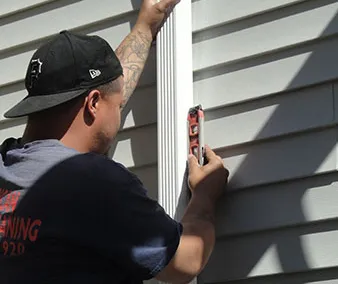 Installer fitting a downspout against the siding