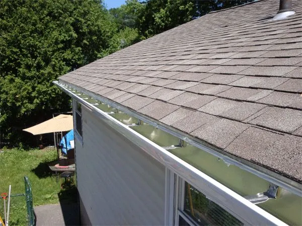 New white seamless aluminum gutter installed along the corner of a home