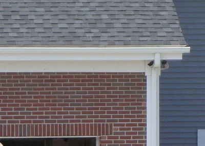 White downspout installed at the corner of a brick home
