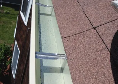 New gutter installed along a red shingle roof