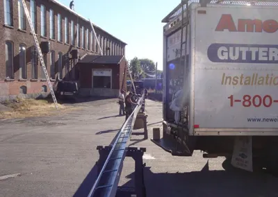 American Gutter truck working between brick mill buildings