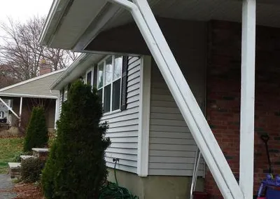 Downspout routed around a white porch post